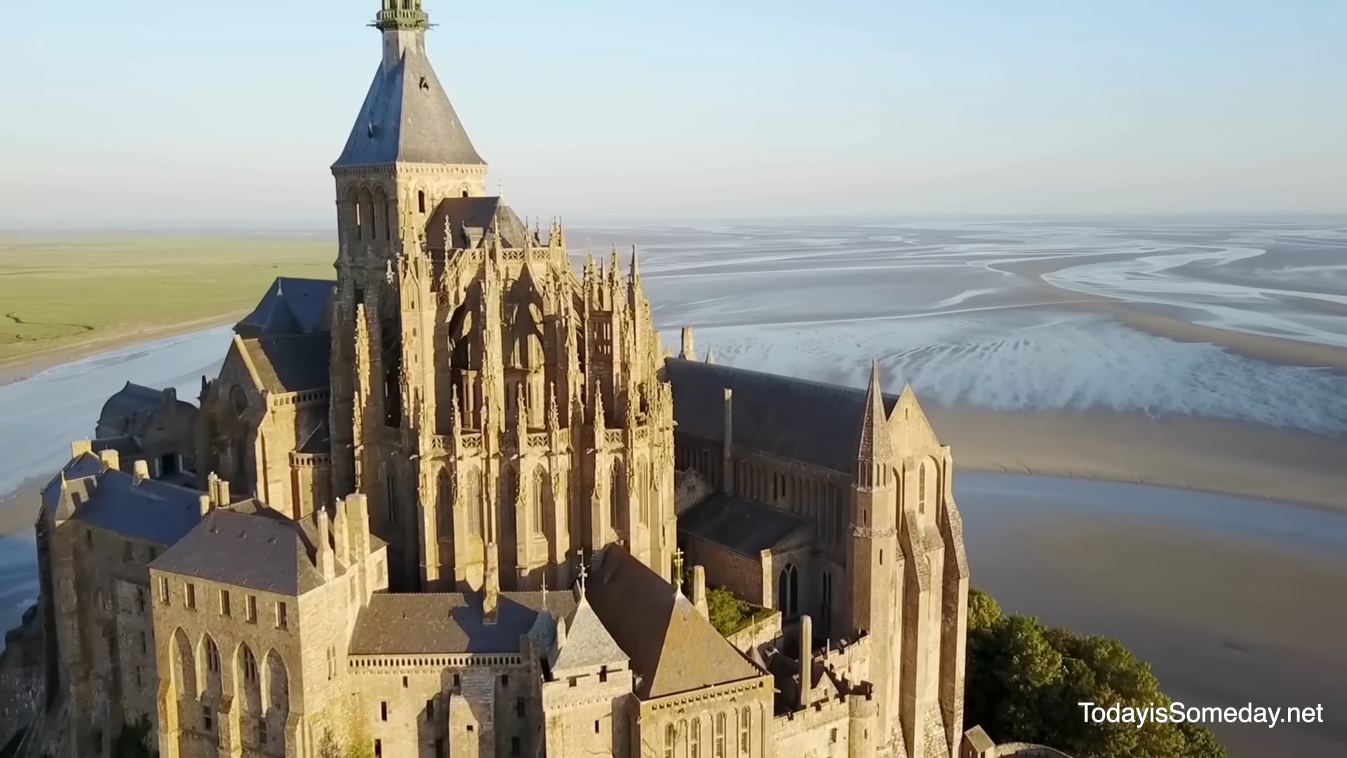 Vue aérienne de l'abbaye du Mont-Saint-Michel en France, avec ses flèches gothiques dominant la baie à marée basse